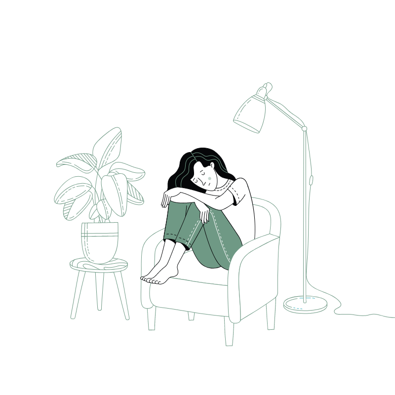 meisje zit met hoofd naar omlaag in kleermakerszit in fauteuil naast plant en staanlamp